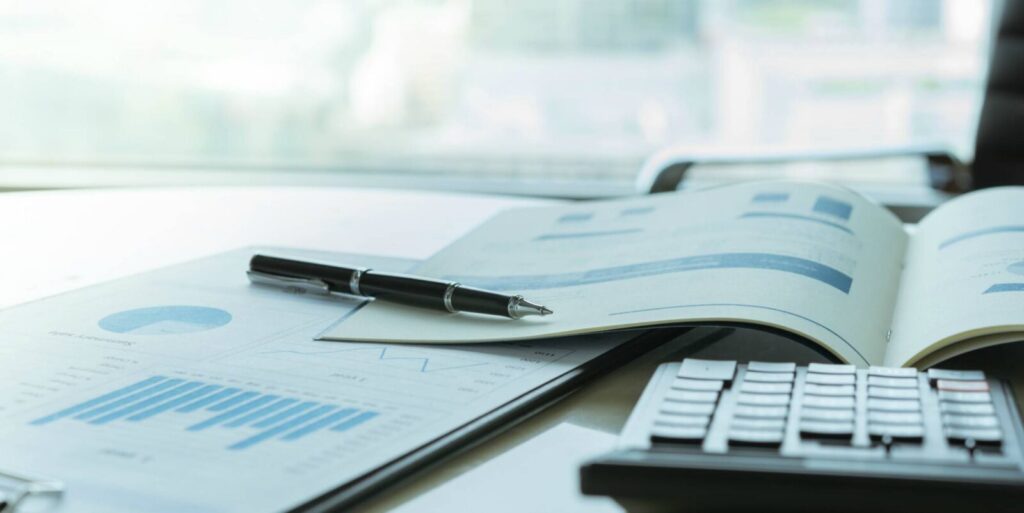 Open financial reports with charts and graphs, a pen, and a calculator on a desk.
