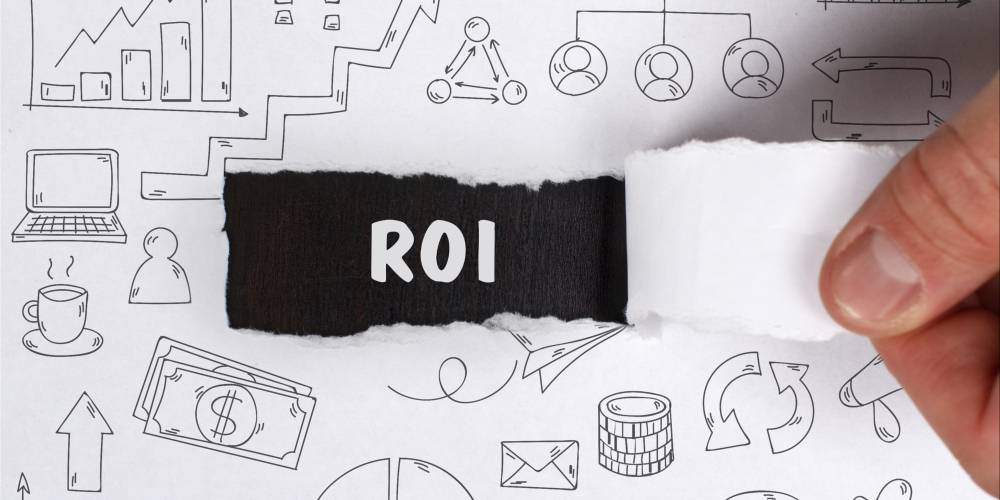 A hand peels back paper revealing the text "ROI" amid various business and finance icons drawn in black on a white background.