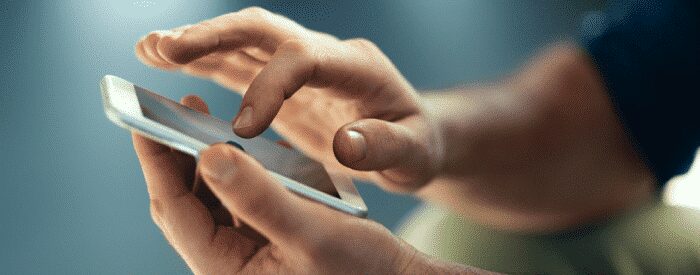 A person using a smartphone, tapping and swiping on the touchscreen with both hands.