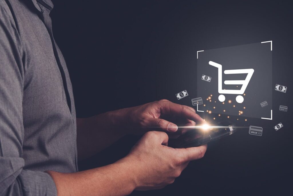 A person using a smartphone with a digital shopping cart icon and floating currency symbols, representing online shopping or e-commerce, highlights how Training Solutions can enhance digital retail experiences.